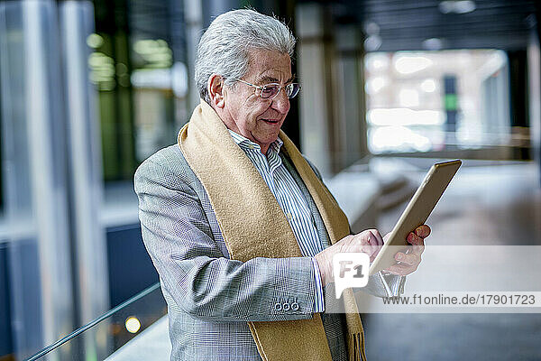 Senior businessman wearing scarf using tablet PC