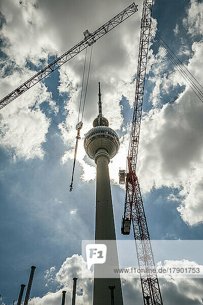 Berlin Television Tower by cranes under sky at Alexanderplatz  Berlin  Germany