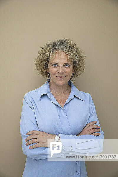 Businesswoman with arms crossed against brown background