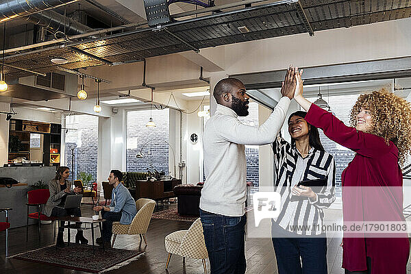 Young businesswomen and colleague high fiving in office