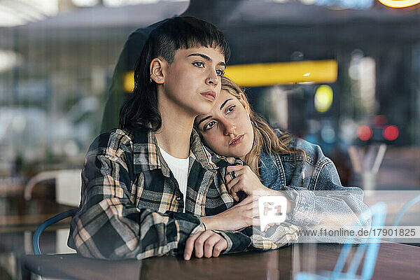 Thoughtful young lesbian couple sitting at table in restaurant