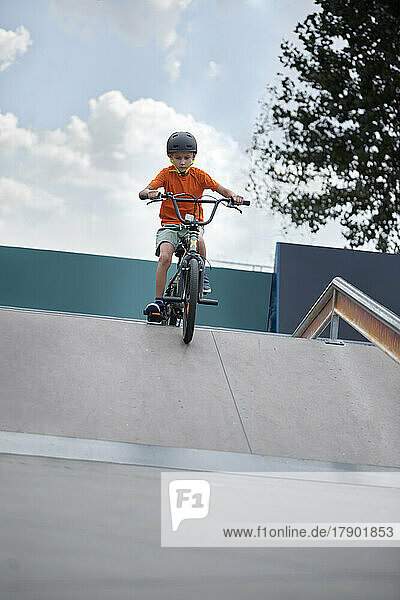 Junge fährt BMX-Fahrrad im Skateboardpark vor dem Himmel