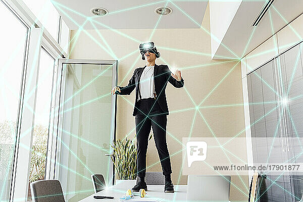 Businesswoman wearing virtual reality simulator standing on table in office