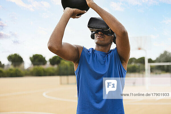 Young man wearing VR headset throwing basketball at sports court