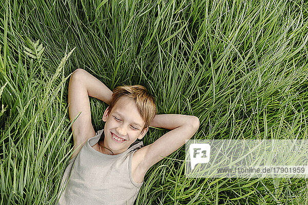Happy boy with eyes closed lying down on grass