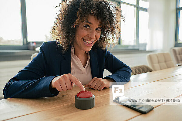 Smiling businesswoman touching buzzer button at office