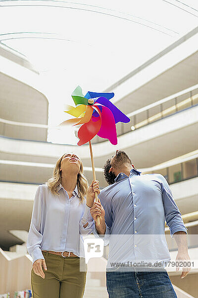 Playful business colleagues blowing multi colored pinwheel toy