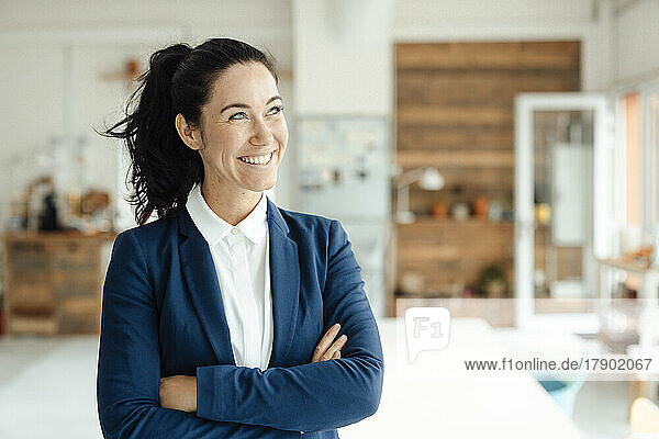 Happy businesswoman standing with arms crossed
