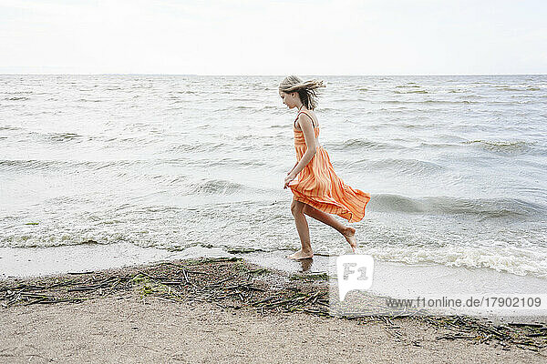 Mädchen spaziert am Strand am Meeresufer entlang