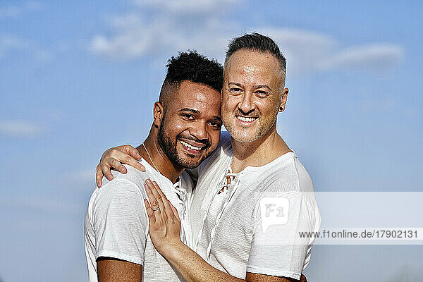 Happy gay couple embracing on sunny day