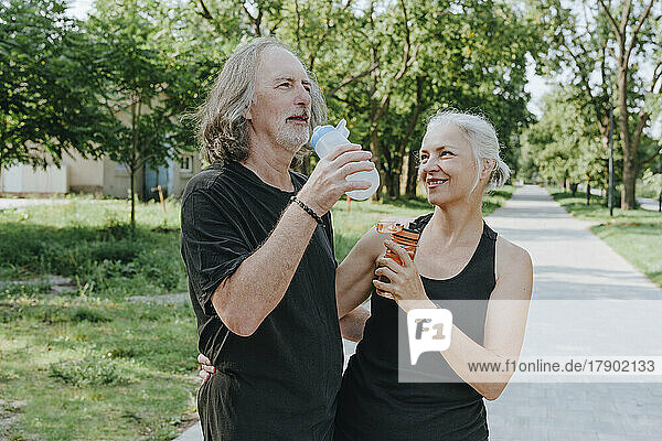 Reife Frau und älterer Mann trinken Wasser im Park