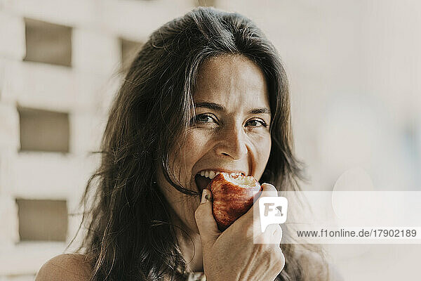 Reife Frau mit langen Haaren  die Apfel isst