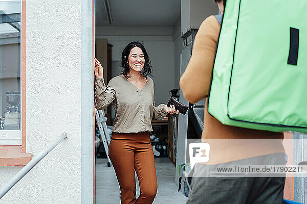 Happy woman in front of delivery man at doorway