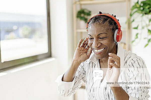 Smiling woman listening music through wireless headphones at home