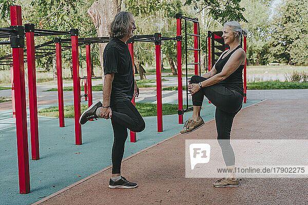 Active couple stretching legs in park