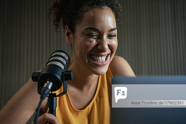 Cheerful radio presenter with microphone podcasting in studio