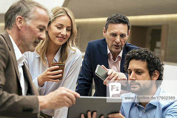 Lächelnde Geschäftskollegen diskutieren über Strategie am Tablet-PC im Büro