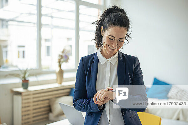 Happy businesswoman checking time on smart watch