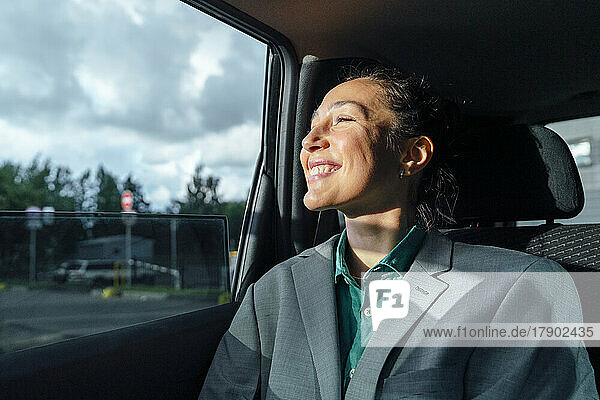 Happy businesswoman sitting in car looking through window