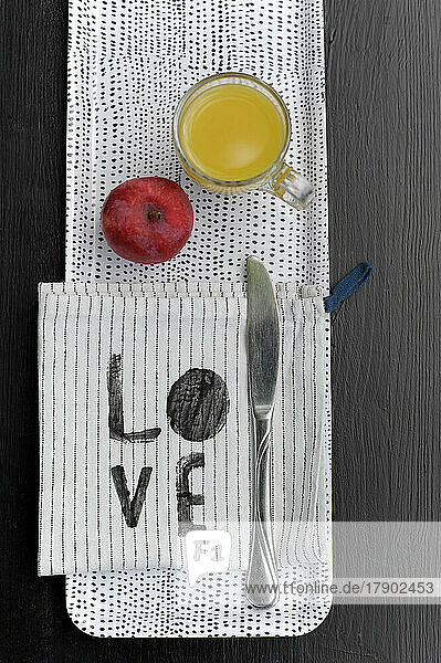 Gepunktetes Tablett mit Apfel  Glas Orangensaft  Geschirrtuch und Tafelmesser