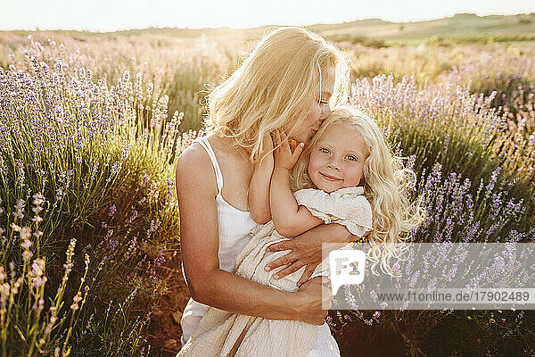 Mother kissing daughter in lavender field