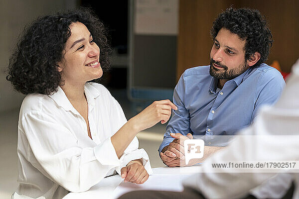Smiling businesswoman discussing ideas with colleagues at office