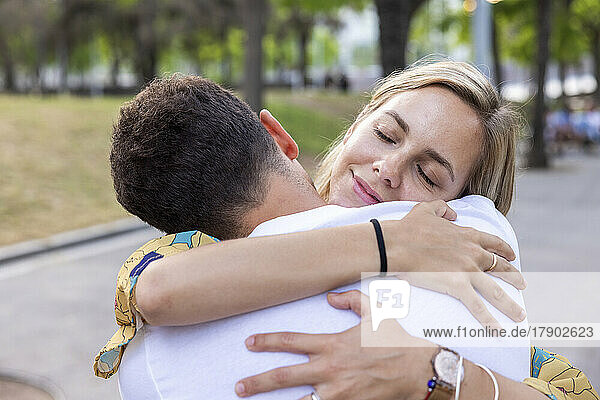 Woman with eyes closed embracing boyfriend at park