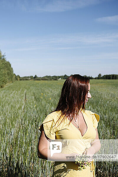 Woman in yellow dress standing in cornfield