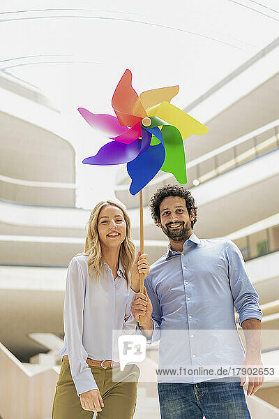 Happy business colleagues holding multi colored pinwheel toy