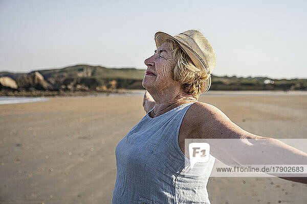 Smiling woman with arms outstretched enjoying at beach
