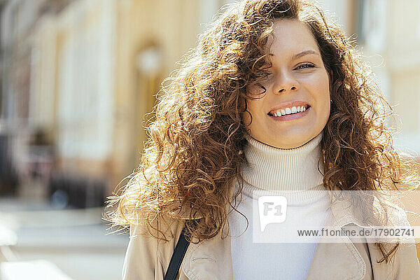 Happy woman with curly brown hair on sunny day
