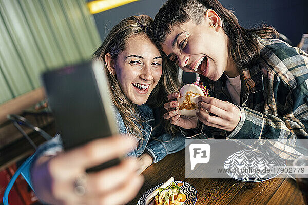 Cheerful lesbian couple taking selfie through smart phone