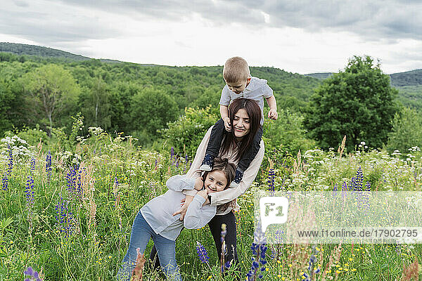 Mother with daughter and son in lupine flowers meadow