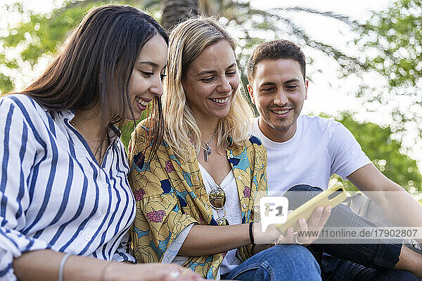 Happy woman sharing smart phone with friends
