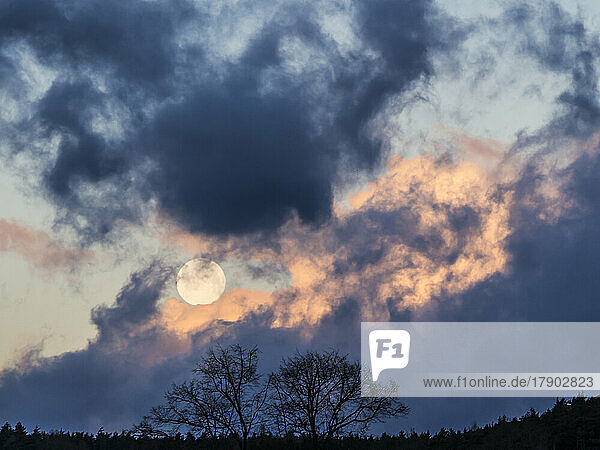 Full moon rising behind storm clouds