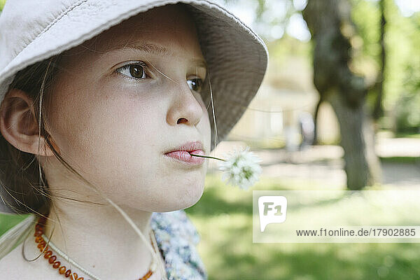 Girl with flower in mouth wearing hat