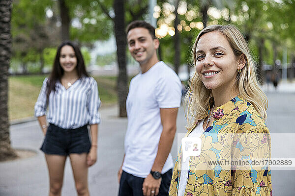 Smiling woman standing in front of friends at park
