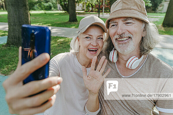 Happy couple talking on video call through smart phone in park
