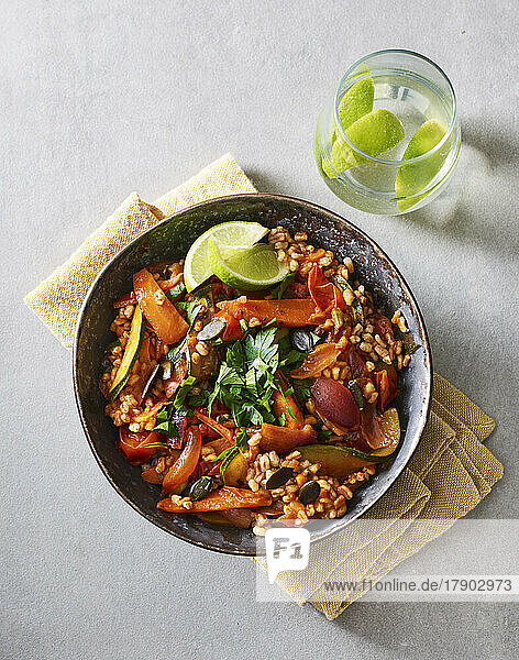 Ready-to-eat bowl of cooked grains with vegetables  pumpkin seeds  parsley and lime