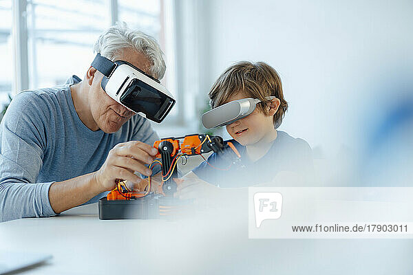 Senior man and grandson with futuristic glasses watching robot model at home