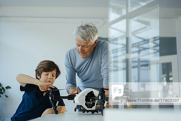 Junge und Großvater untersuchen Drohne zu Hause auf dem Tisch