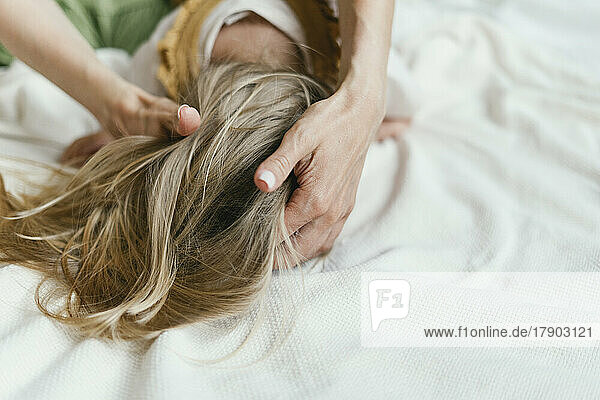 Mutter bindet ihrer Tochter im Bett die Haare