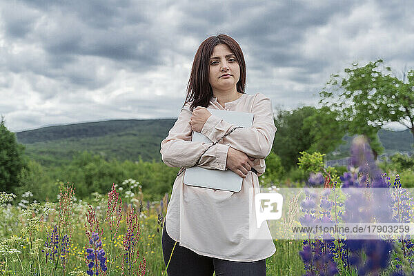Young freelancer chained with laptop amidst flowers