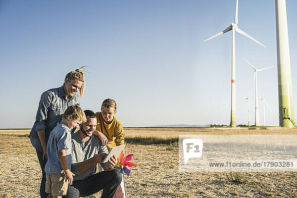 Smiling family using digital tablet in wind park