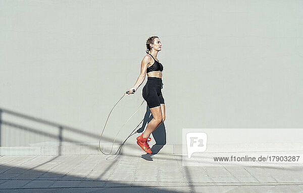Young athlete skipping rope on sunny day