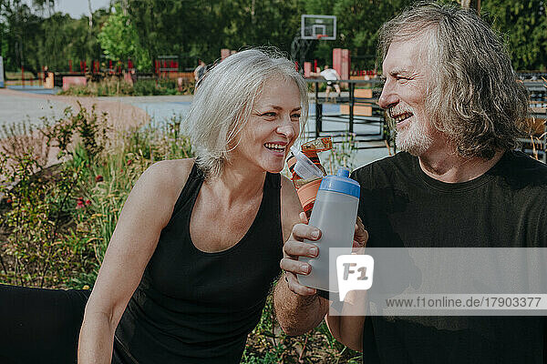Happy couple drinking water in park
