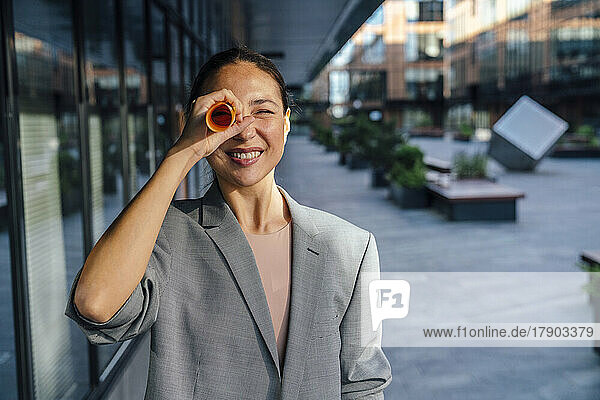 Smiling businesswoman looking through rolled paper