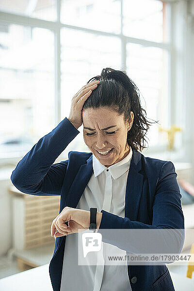 Stressed businesswoman looking at smart watch