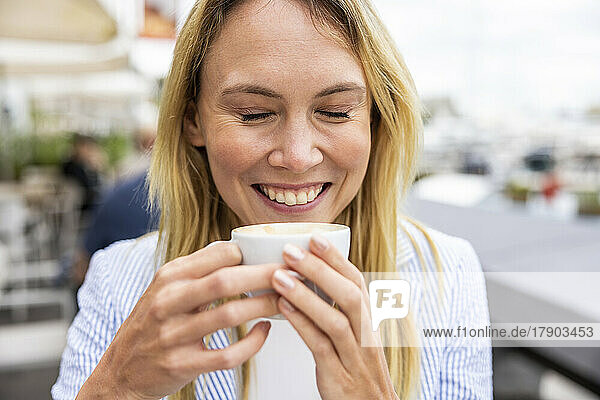 Happy businesswoman with eyes closed holding coffee cup