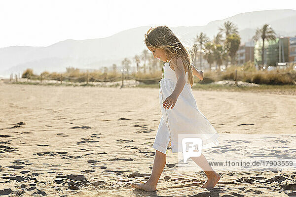 Girl with long hair walking at beach on sunny day